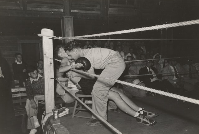 Historische zwart-wit foto van een bokswedstrijd vechtsporten training in actie waarbij een bokser in de hoek wordt aangevallen in de ring 