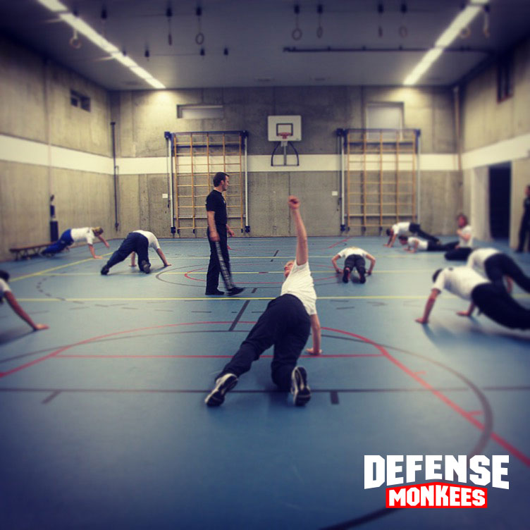 Krav Maga groepsles bij DefenseMonkees waarbij cursisten fysieke kracht- en conditietraining uitvoeren onder begeleiding van een instructeur in de sportschool.