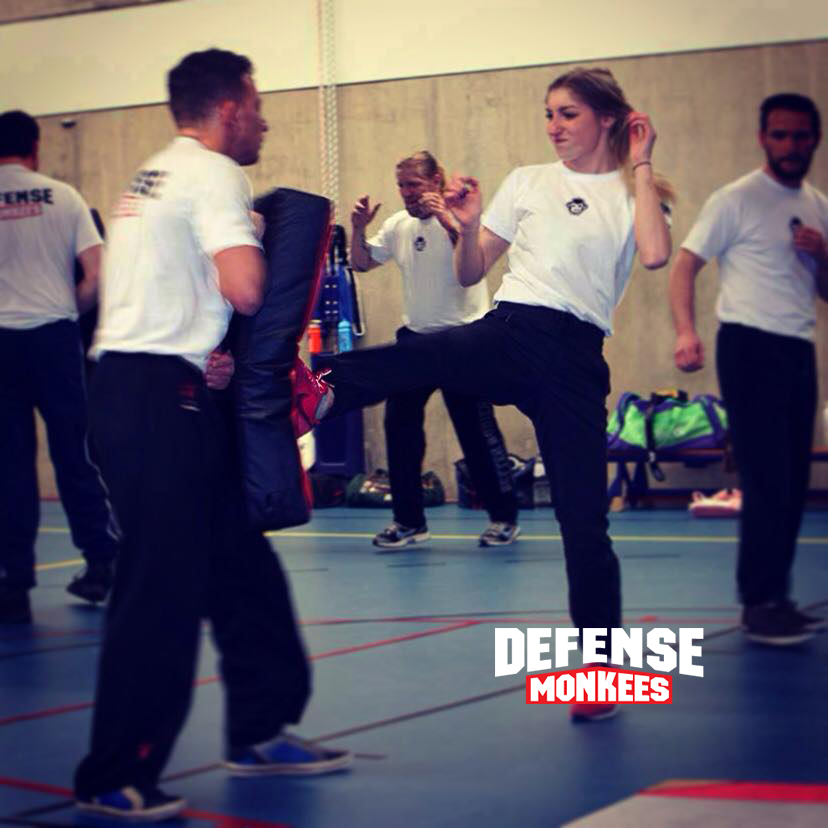 Vrouw traint een krachtige Krav Maga traptechniek bij DefenseMonkees tijdens een groepsles zelfverdediging, onder begeleiding van instructeurs in de sportschool.